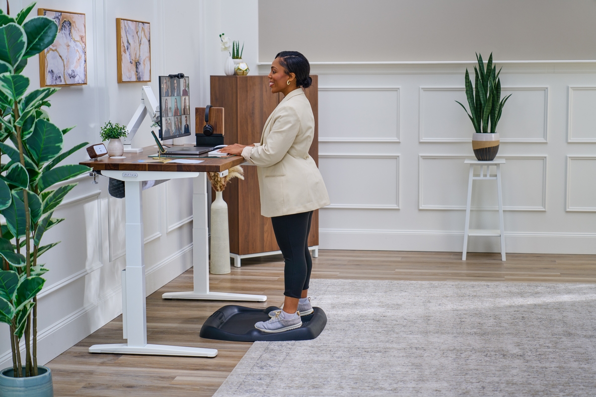 Person standing at an uplift standing desk working.