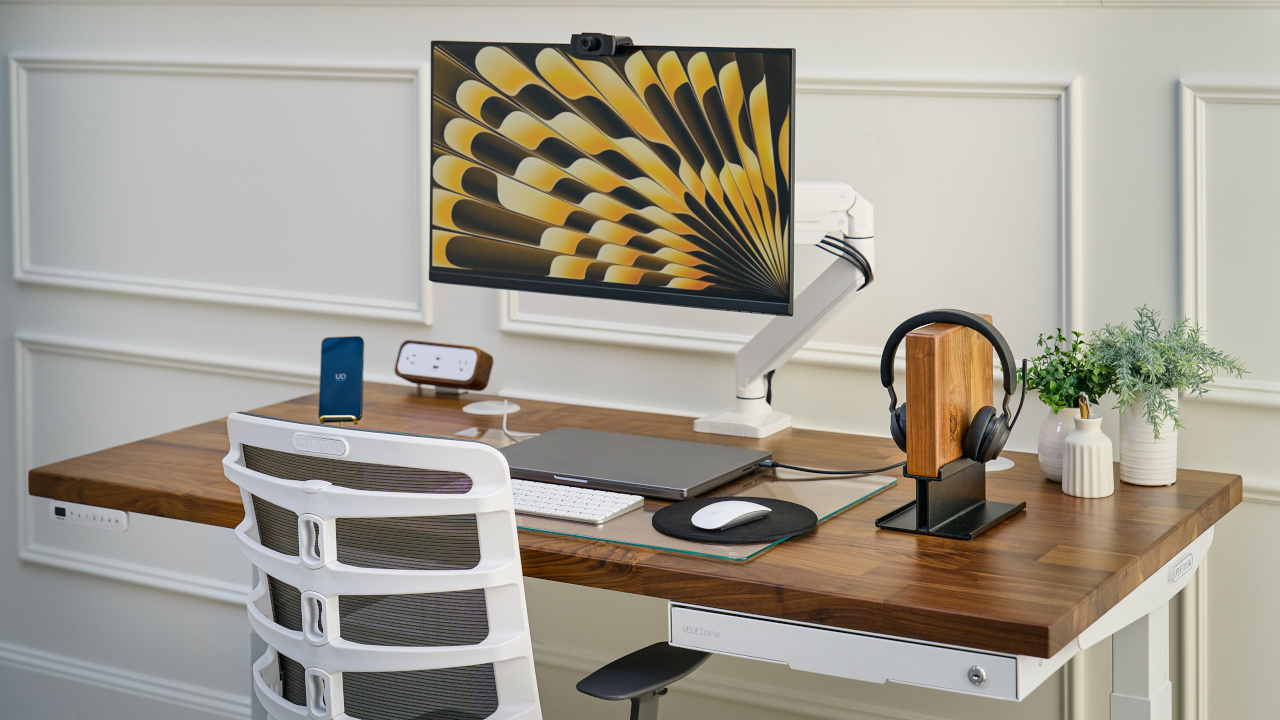 White Crestview Monitor Arm clamped onto Uplift Standing Desk to add more usable desk space.