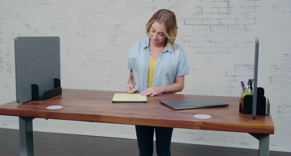 Someone working at a desk with two dark gray Desktop Acoustic Privacy Panels