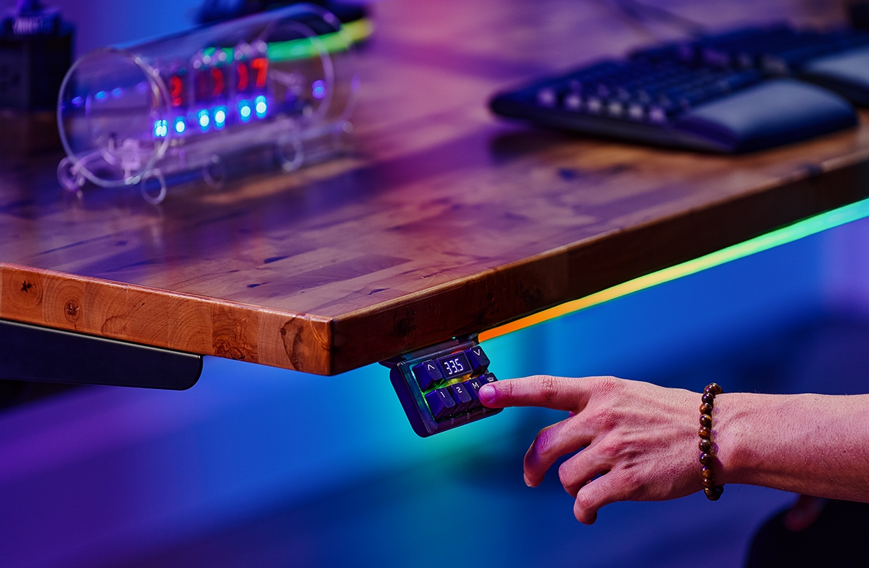 Person pressing preset keypad button on an Uplift Standing Desk.