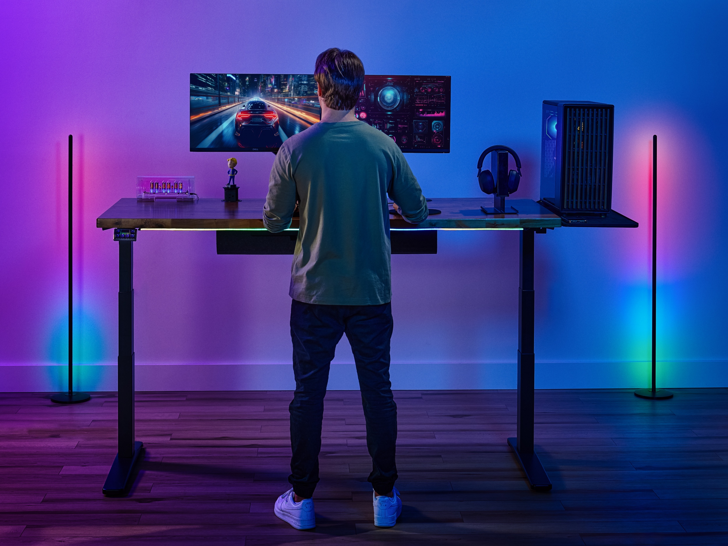 Man standing at a V3 2-leg standing desk playing a video game in a room lit with a gamer aesthetic