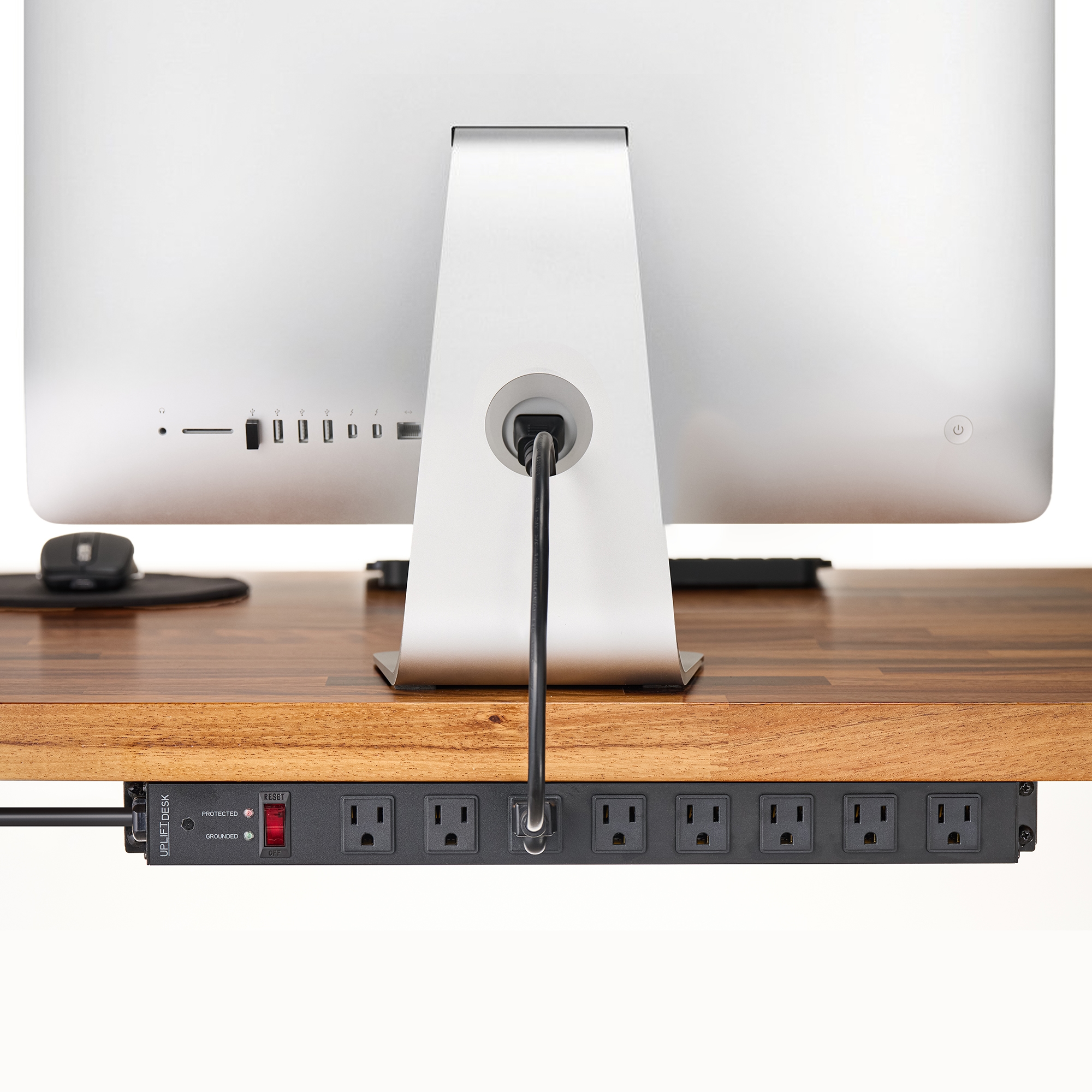 Surge protector mounted to the frame of an UPLIFT standing desk