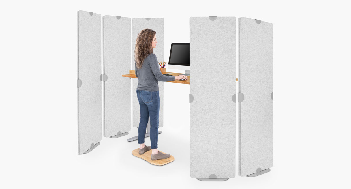 Freestanding Acoustic Privacy Panels in light gray surrounding someone working at a height adjustable desk