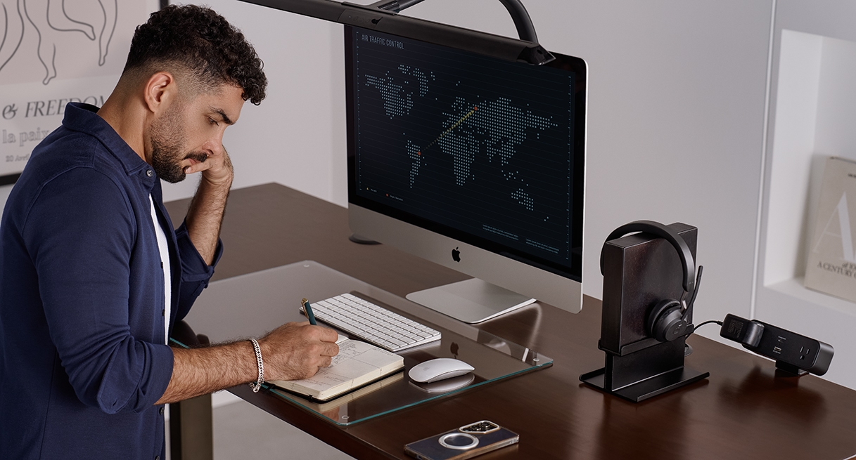 Person standing and writing at an Uplift Standing Desk in Industrial with a Dark Rubberwood Butcher Block desktop.