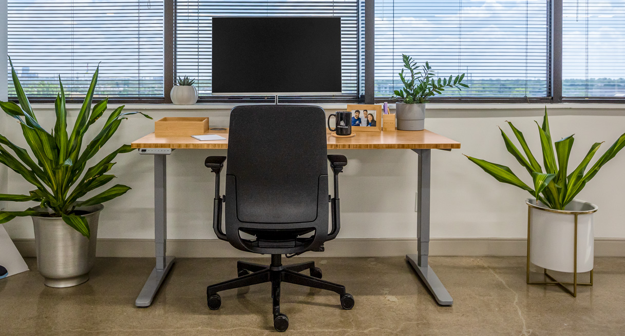 A bamboo standing desk with organizer set and gray frame