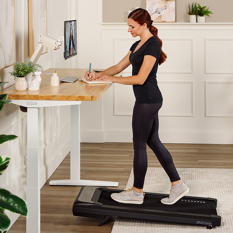 Person walking on a walking pad working at an Uplift Standing Desk.