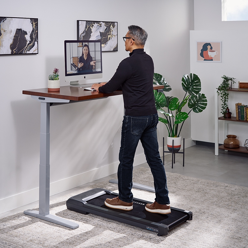 Person walking on a walking pad working at an Uplift Standing Desk.
