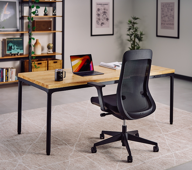 Black Bolan Ergonomic Chair positioned in front of an UPLIFT Standing Desk in a modern home office