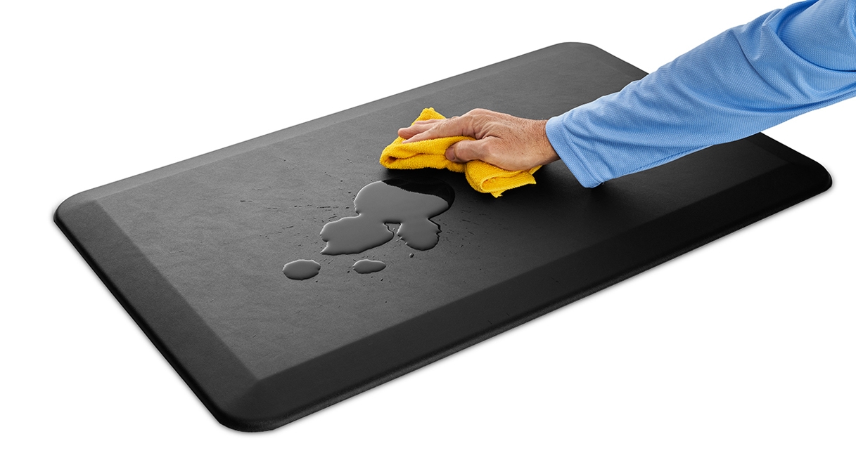 A hand wiping down the waterproof surface of the anti-fatigue Standing Desk Mat