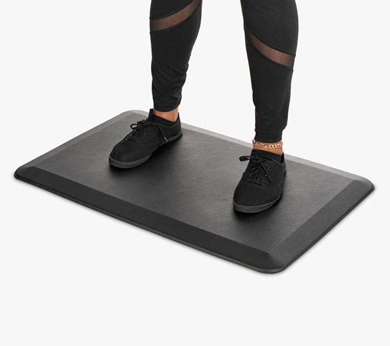 A person standing on an anti-fatigue standing desk mat