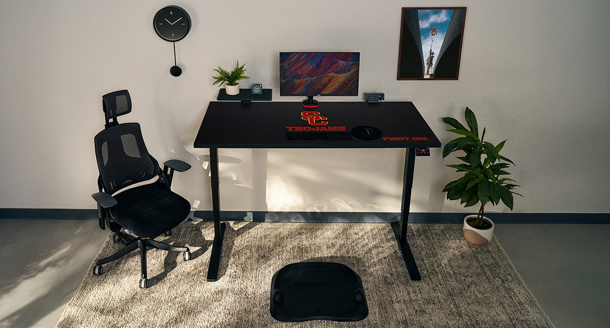 Small office featuring an UPLIFT Standing Desk with USC Trojans logo.