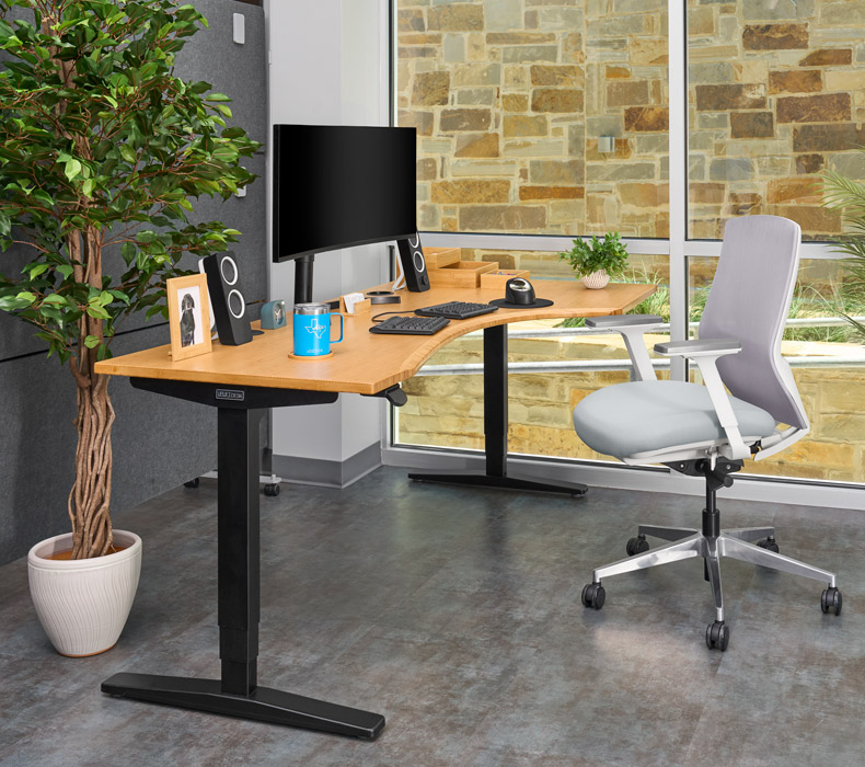 A Bamboo UPLIFT Curved Corner Standing Desk with a white Envoke Chair in an office