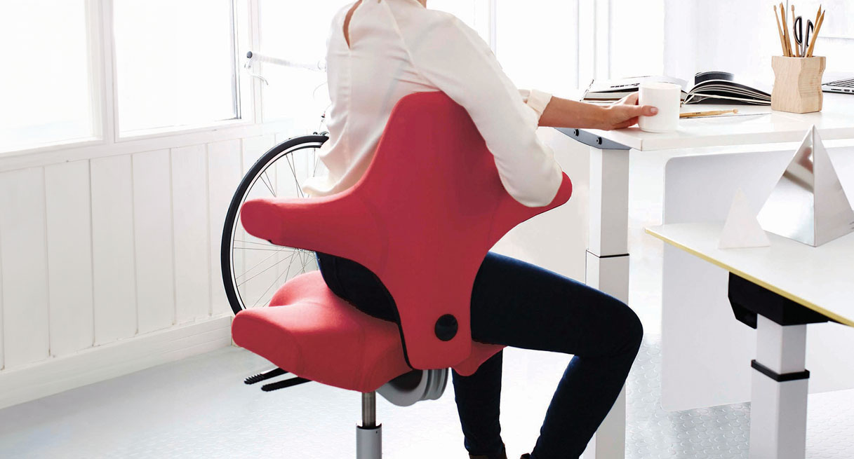 A person in an ergonomic HAG Capisco Chair working at her desk