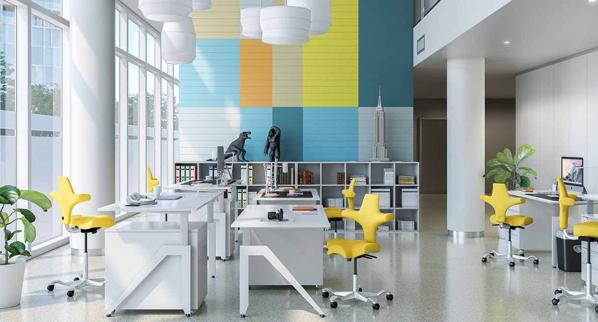 An open office layout with standing desks and Hag Capisco Chairs
