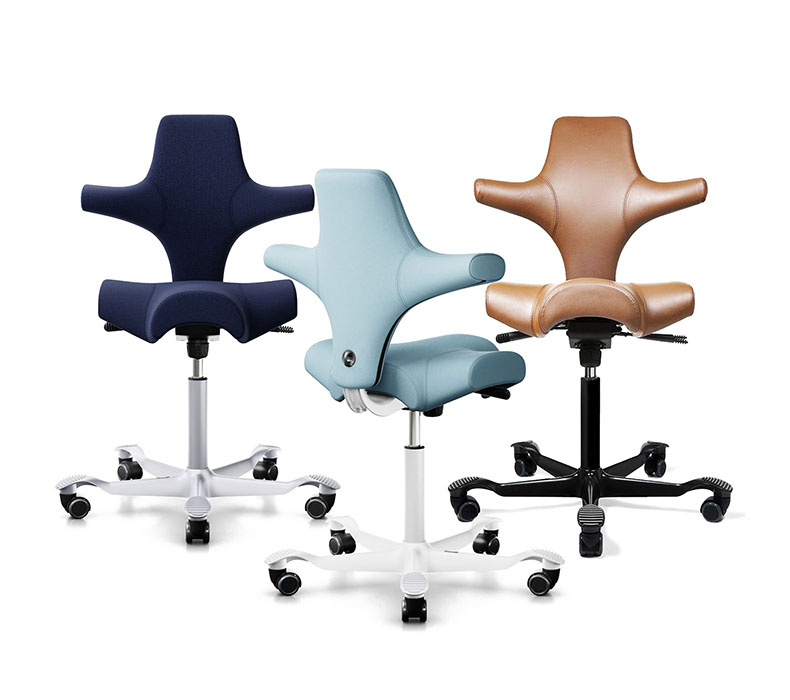 Three ergonomic HAG Capisco chairs in dark blue, light blue, and paloma leather