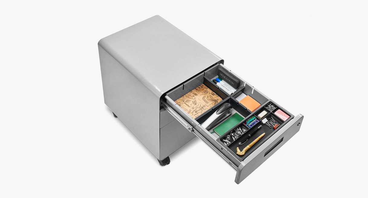 Someone placing folders in a gray file cabinet's fully extended open bottom drawer