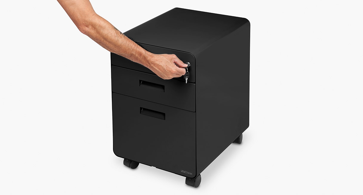 Someone using the top drawer lock on the locking three drawer file cabinet