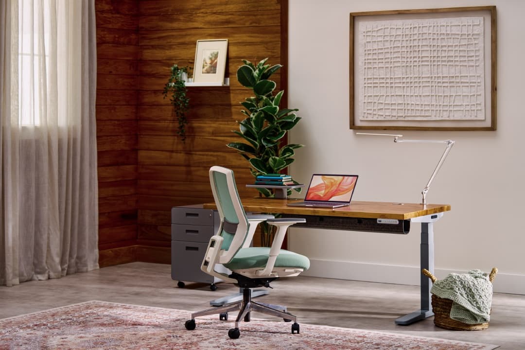 Uplift Standing Desk in Gray with a Reclaimed Birch Butcher Block desktop in a cozy office setting.