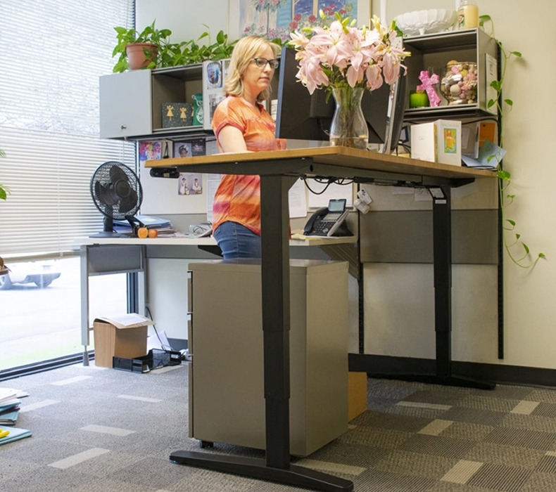 Office administrator working at a height-adjustable desk by UPLIFT Desk.